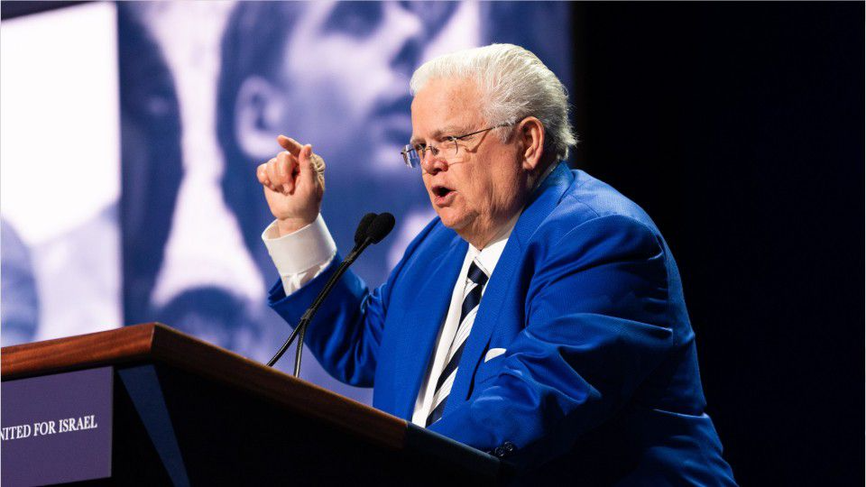 John Hagee speaking in a mic with hand in the air