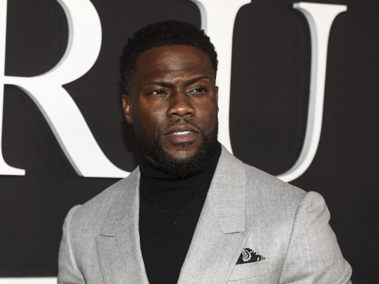 Kevin Hart wearing a grey suit in an event ceremony