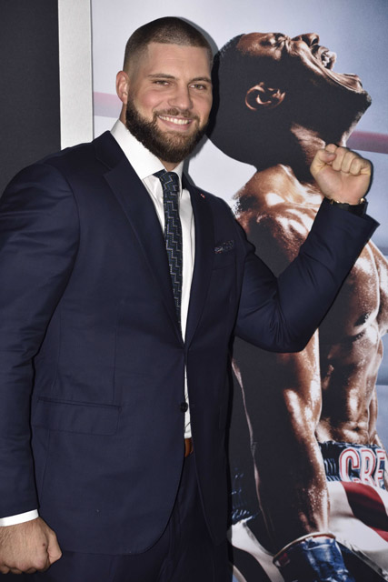Florian Munteanu posing in front of the Creed II movie cover featuring Michael B. Jordan