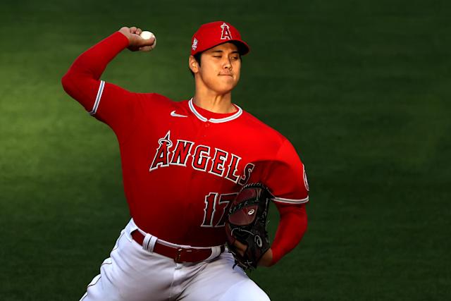 Shohei Ohtani wearing a red uniform and a red cap while throwing the baseball ball