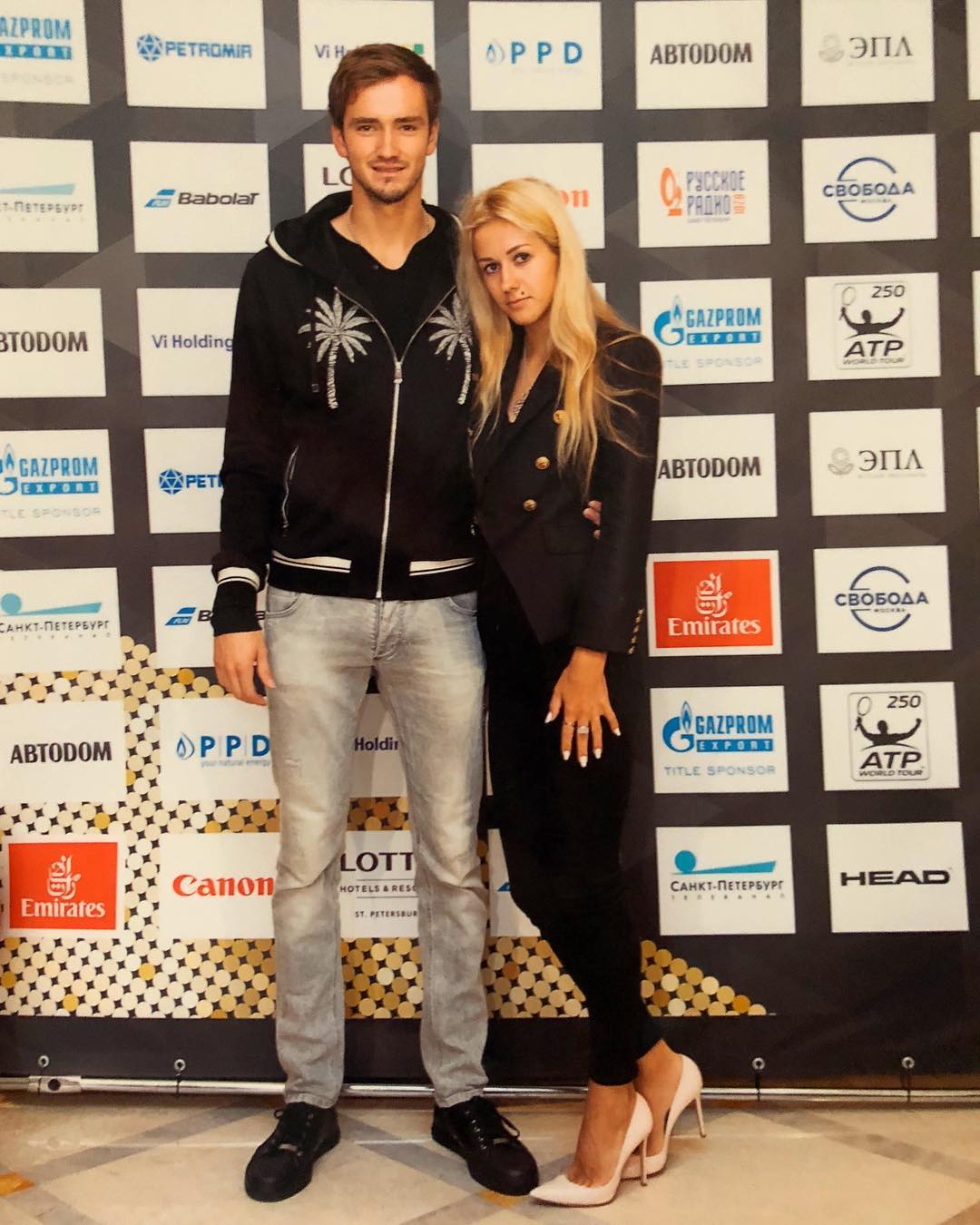 Daria Medvedev wearing a black coat and pants with her husband who is wearing a black jacket and gray pants