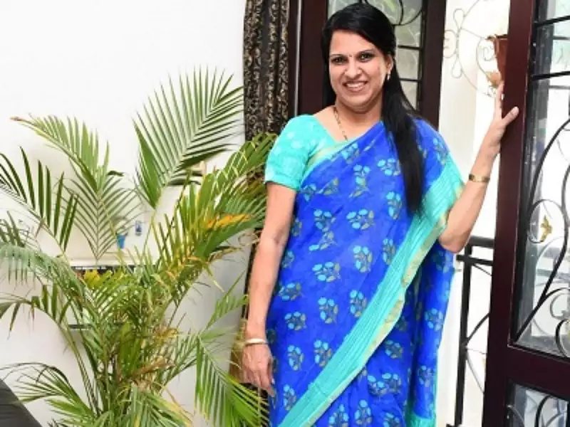 Bharathi Baskar with her blue sari and a nice smile while leaning on the veranda door