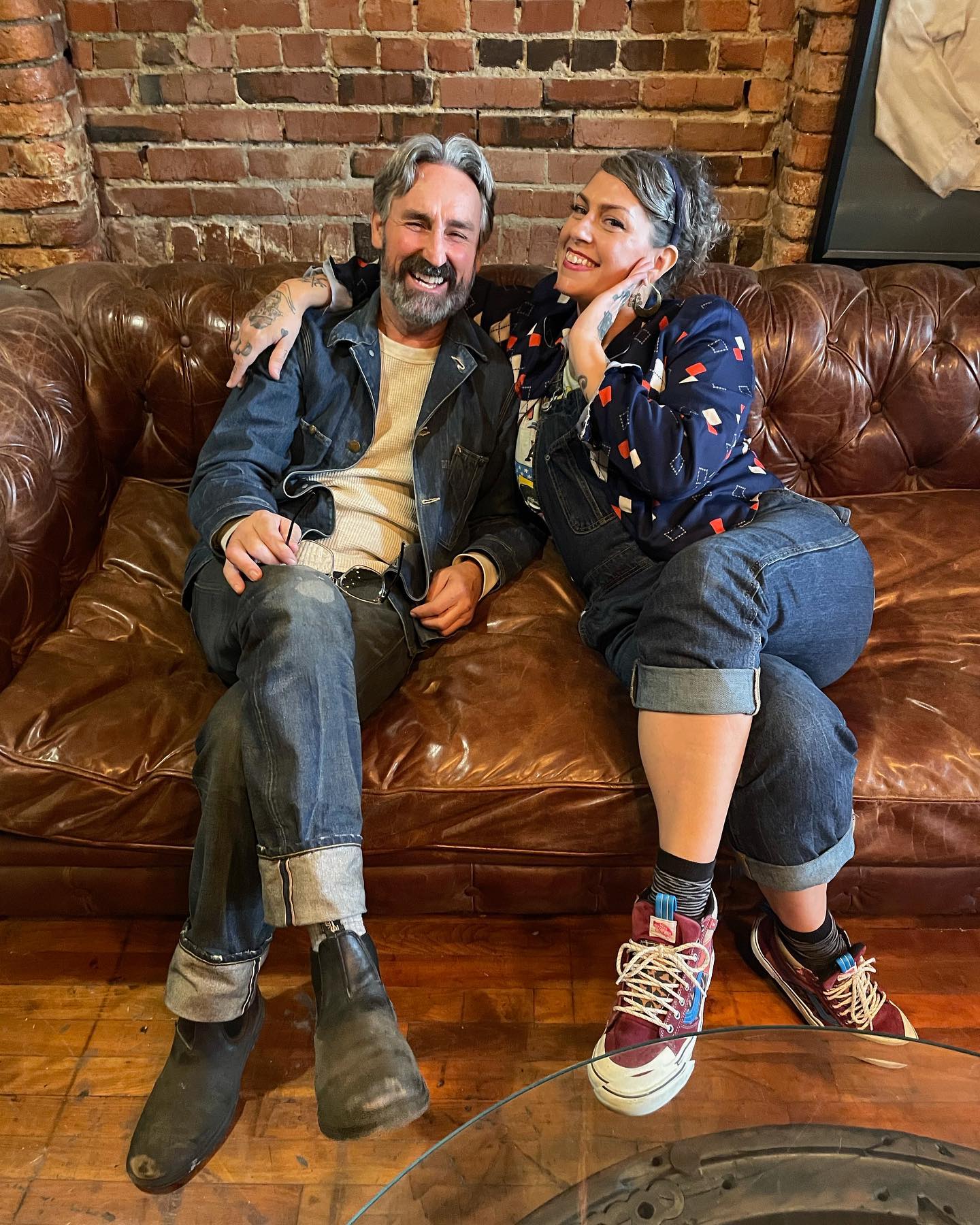 Danielle Colby poses with Mike Wolfe while sitting on a brown leather couch