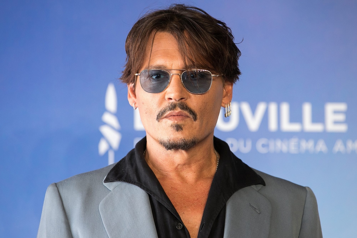 Johnny depp in a gray suit with earring and blue tinted sun glasses