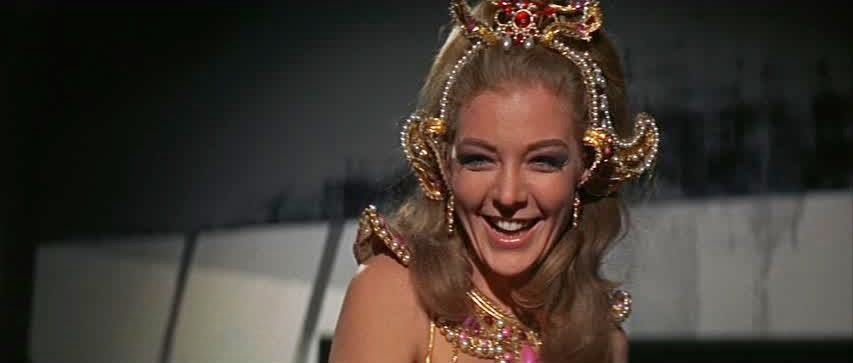 Joanna Pettet laughing and wearing a beaded crown and dress