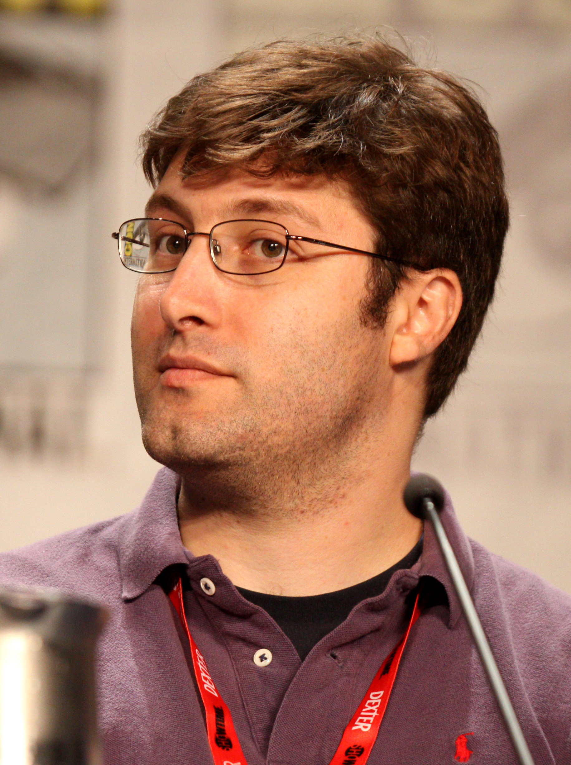 Michael Koman wearing glasses and talking in a mic