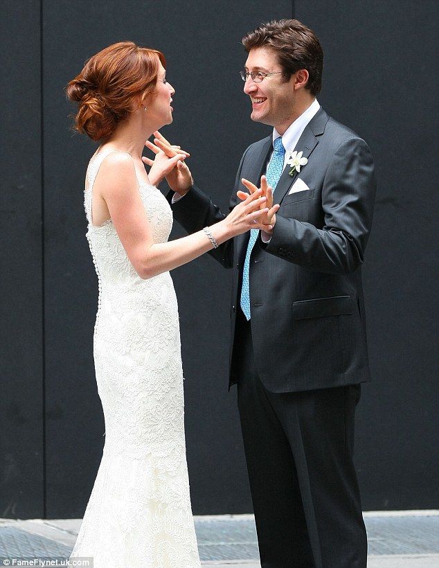 Michael Koman holding hands with Ellie Kemper at their wedding wearing black dress