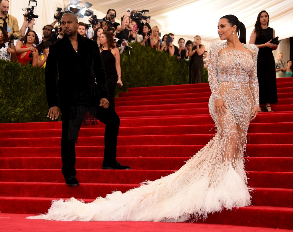 Kim kardashian in a white see through feathered gown and kanye west in a black suit