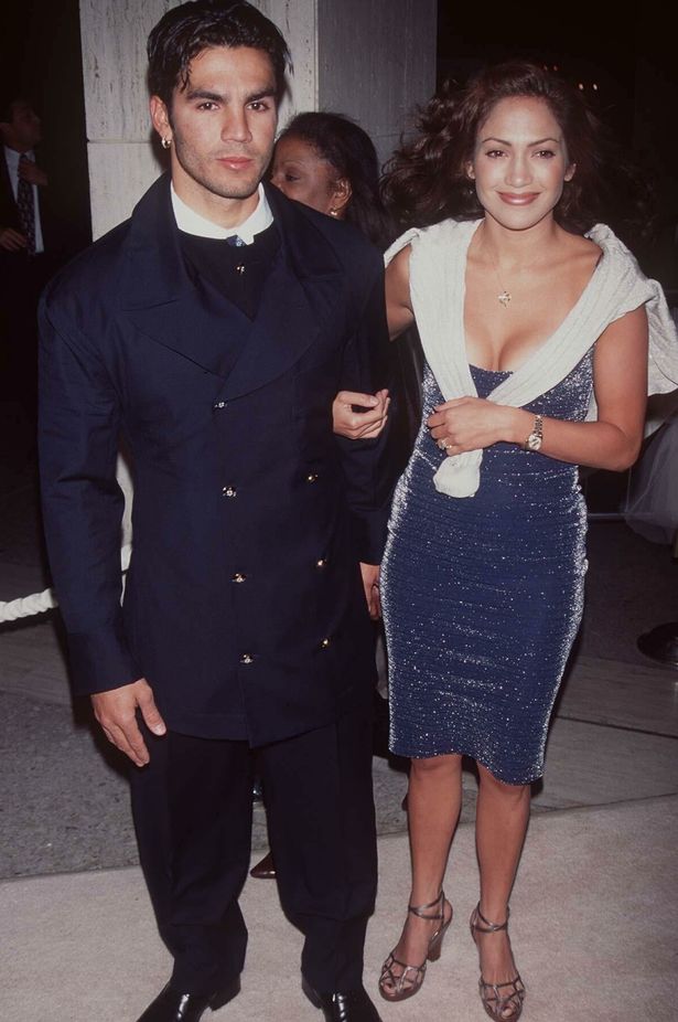 Jennifer Lopez standing beside Ojani Noa holding his arm 