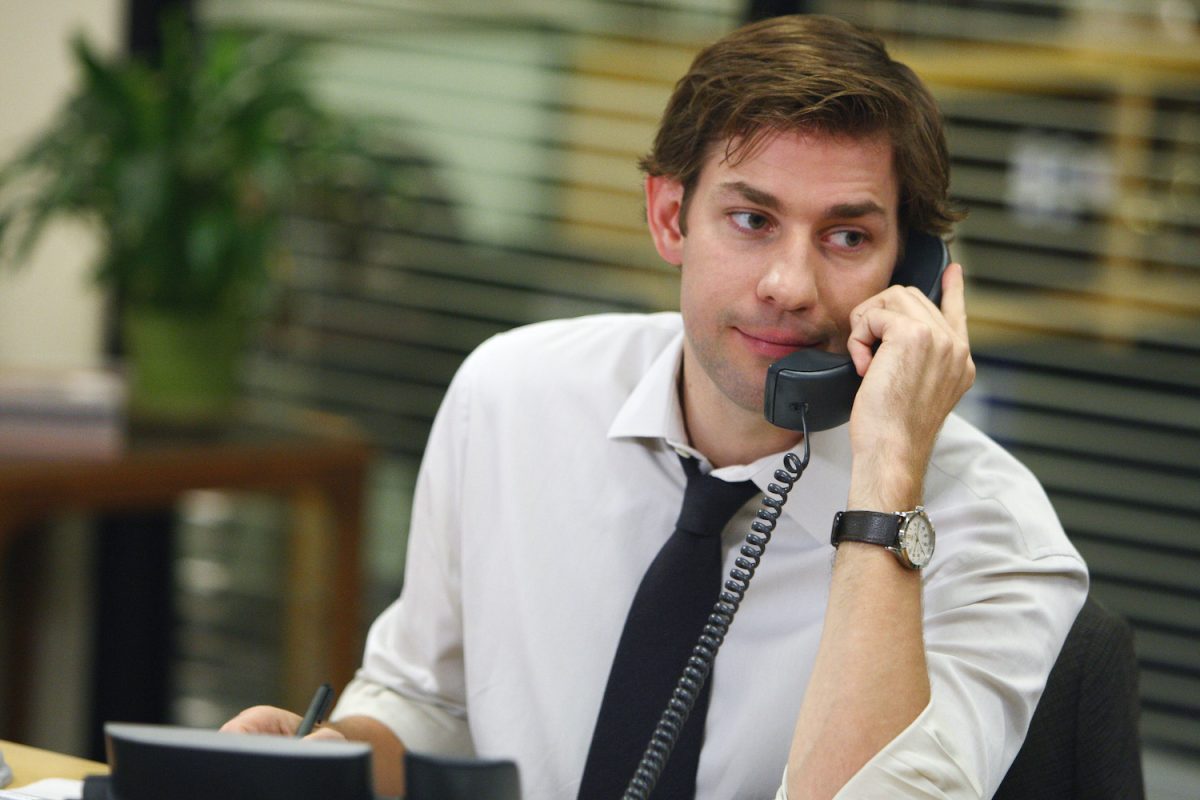 John Krasinski in a white long sleeves with black neck tie with a telephone in his ear