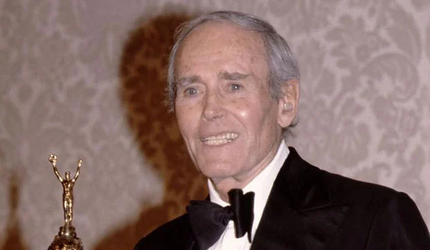 Henry Fonda wearing a suit and holding a gold trophy