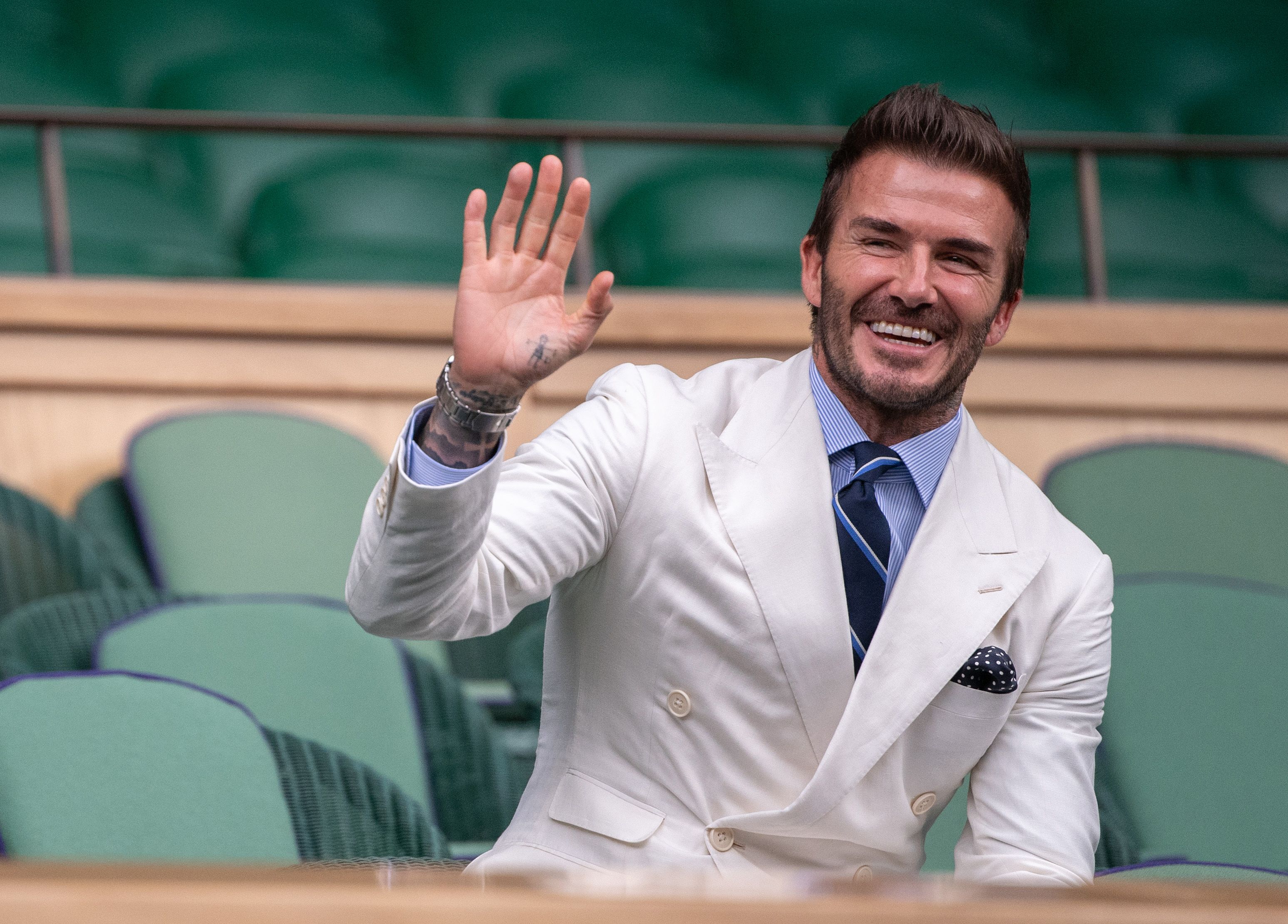 David Beckham wearing a white suit while waving