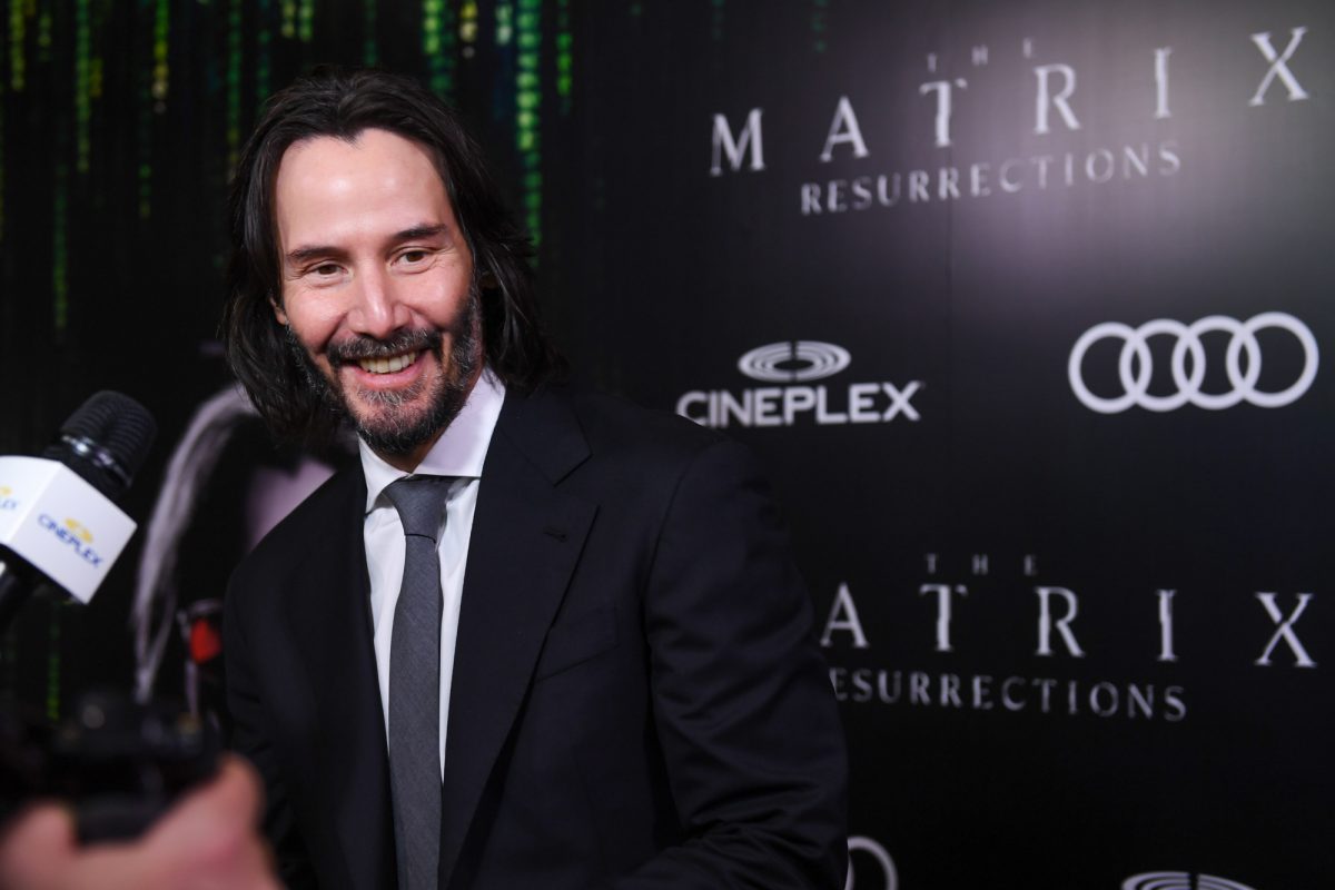 Keanu Reeves in a suit while smiling in the Matrix premiere