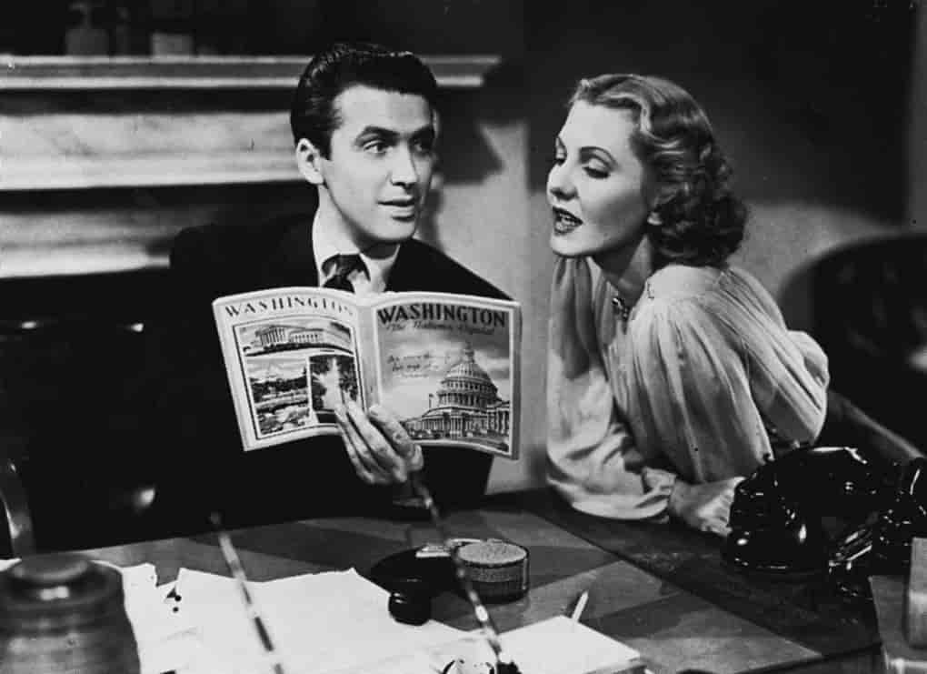 James Stewart holding a magazine and looking at the woman beside him