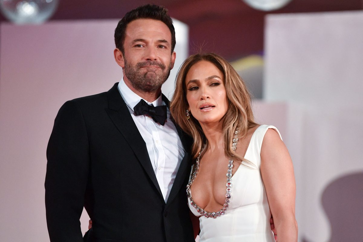 Ben Affleck in black suit smiling and Jennifer Lopez in white and silver attire