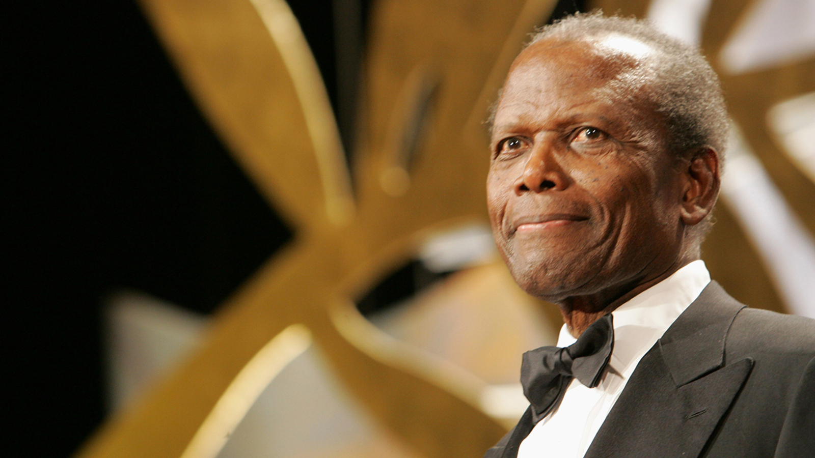 Sidney Poitier wearing a bow tie and suit on stage