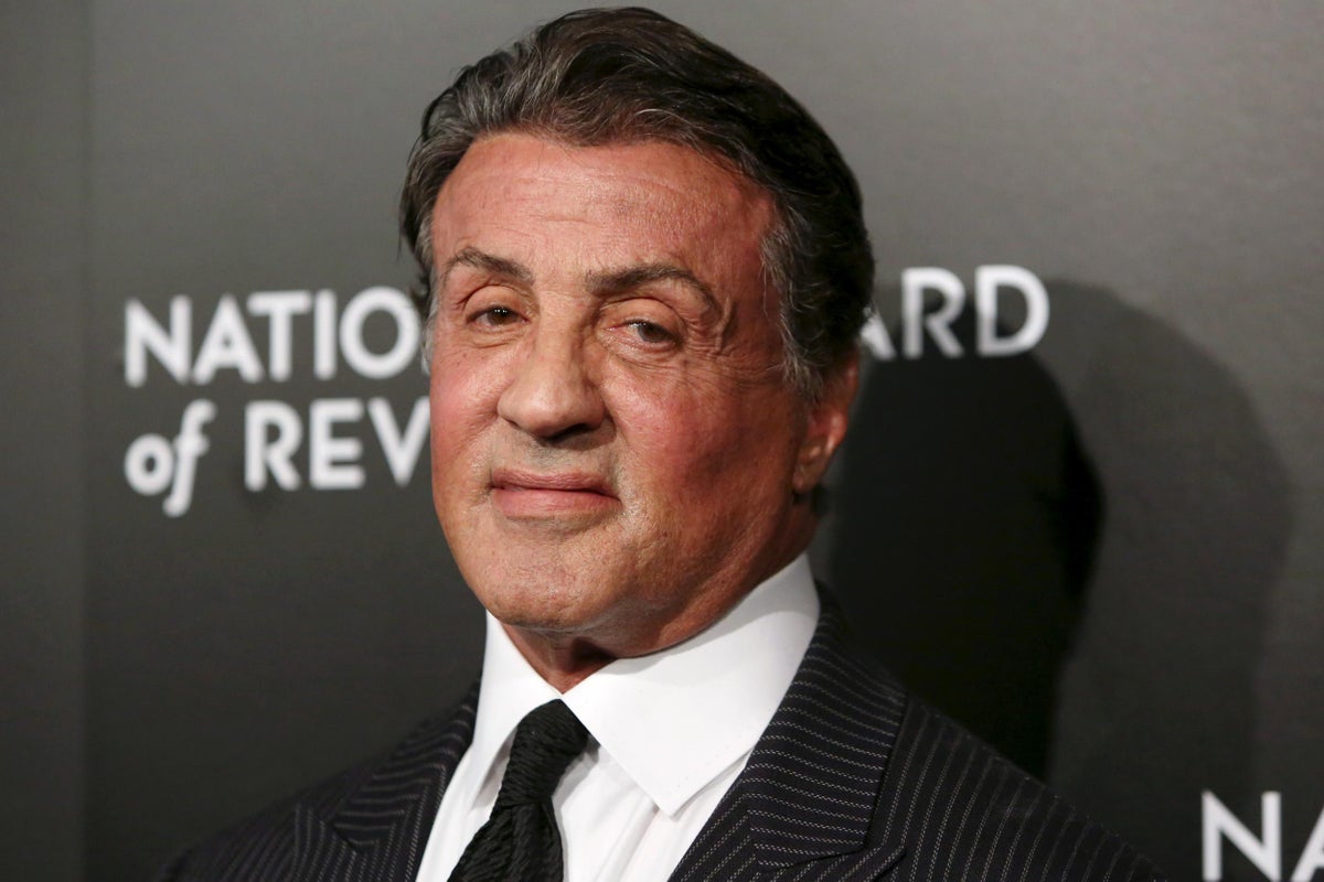 Sylvester Stallone in a suit while smiling