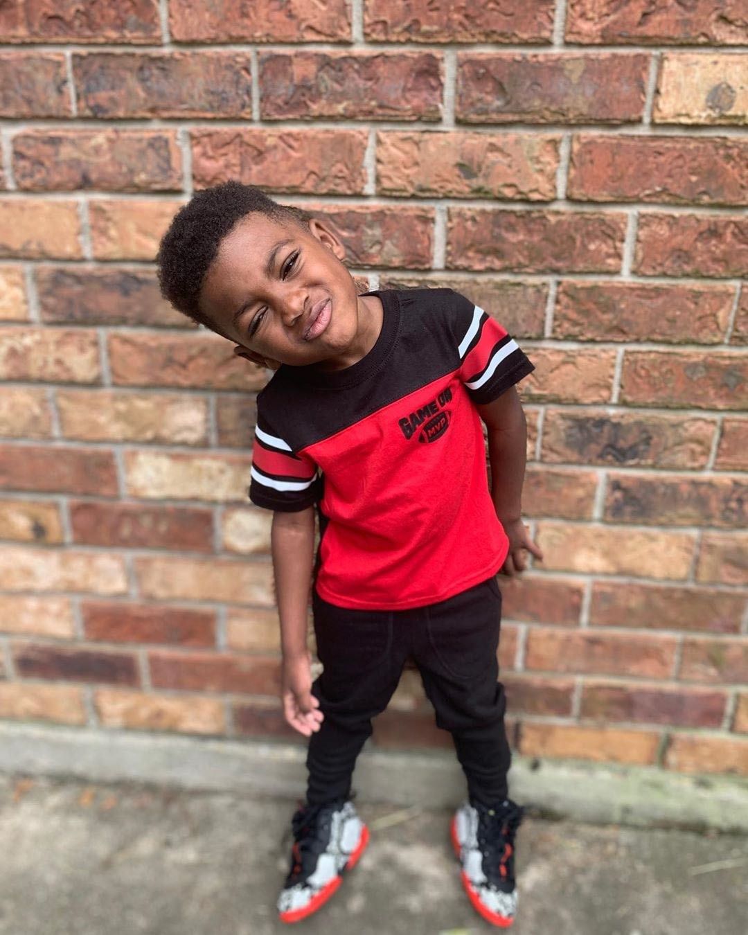 Kayden Gaulden standing in front of a brick wall wearing red and black shirt