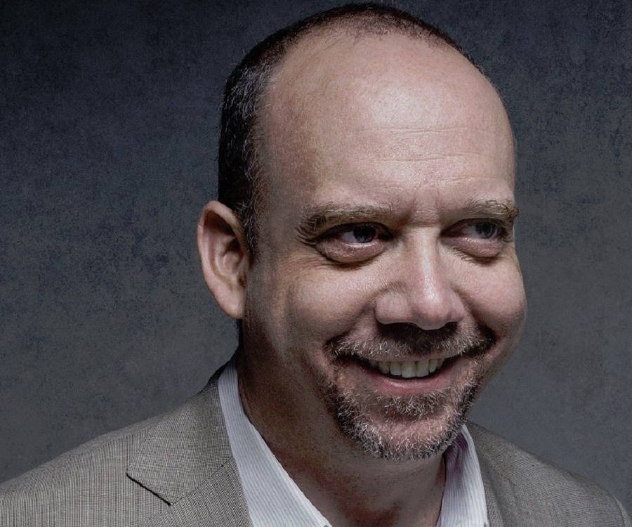 Paul Giamatti wearing a brown suit and smiling