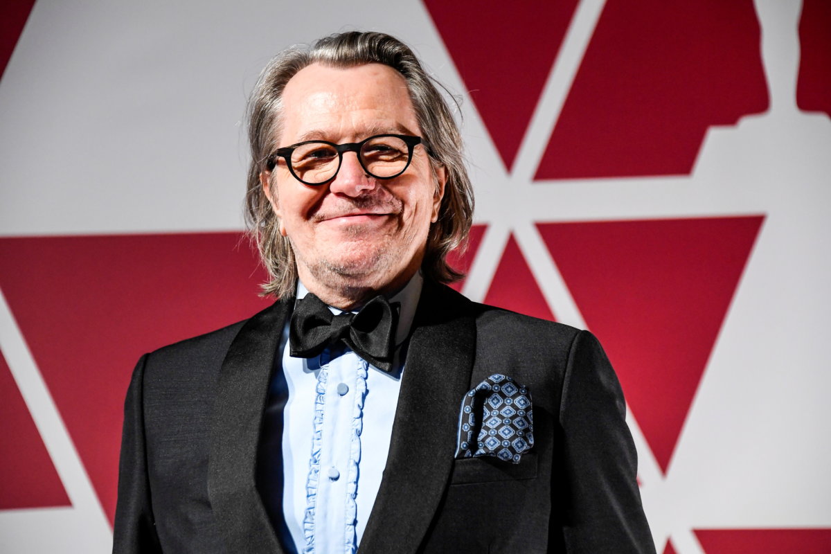Gary oldman in a suit with a bow tie while smiling