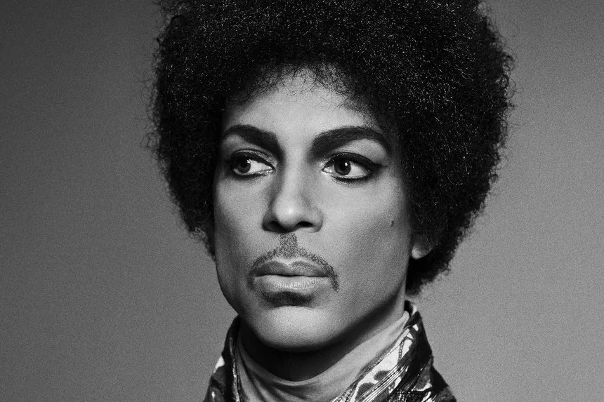 Headshot of Prince with thick eyebrows, eyeliner, and well-trimmed mustache