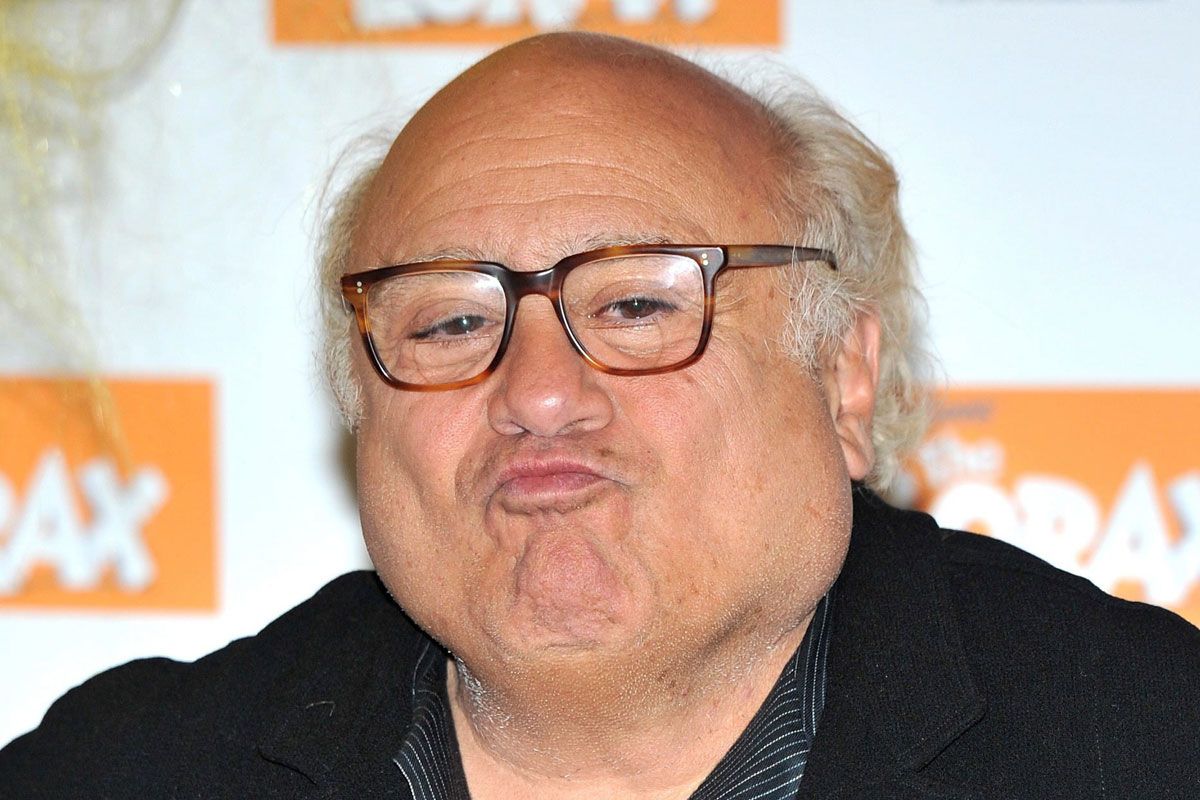 Danny DeVito in a suit and eyeglasess while pouting his lips