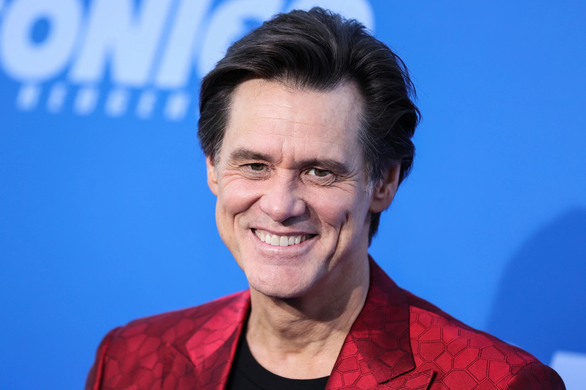Jim Carrey wearing a red suit at one of his movie's premier