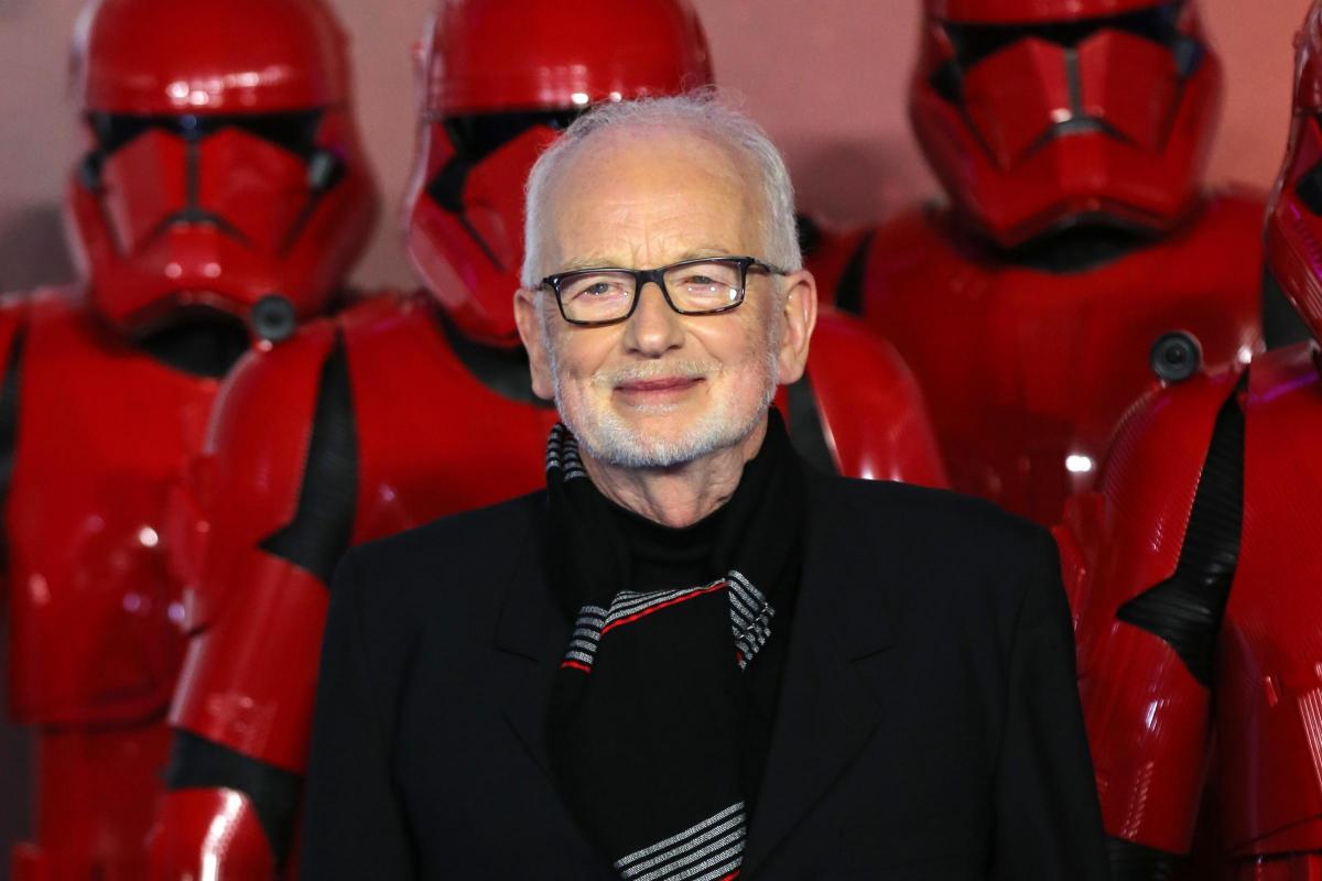 Ian McDiarmid standing wearing black in front of stormtroopers in red