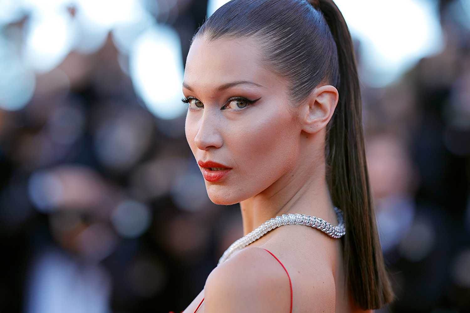 Bella Hadid wearing a red dress, a chain necklace and her hair tied in a high-ponytail