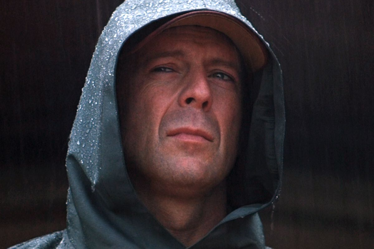 Bruce willis wearing a cap and a raincoat
