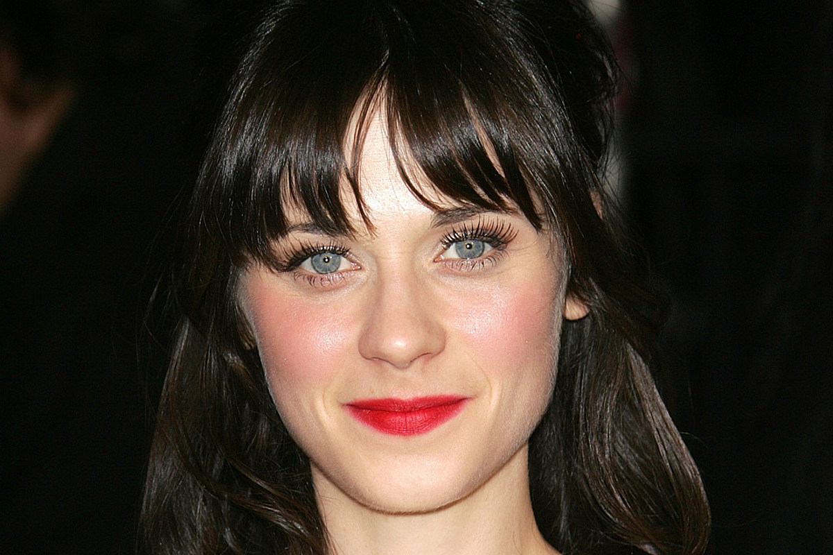 Zooey Deschanel with bangs and red lipstick while smiling