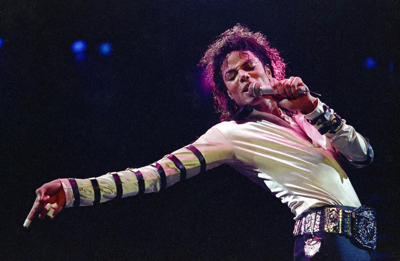 Michael Jackson wearing a longsleeve top and a big beaded belt while performing on the stage