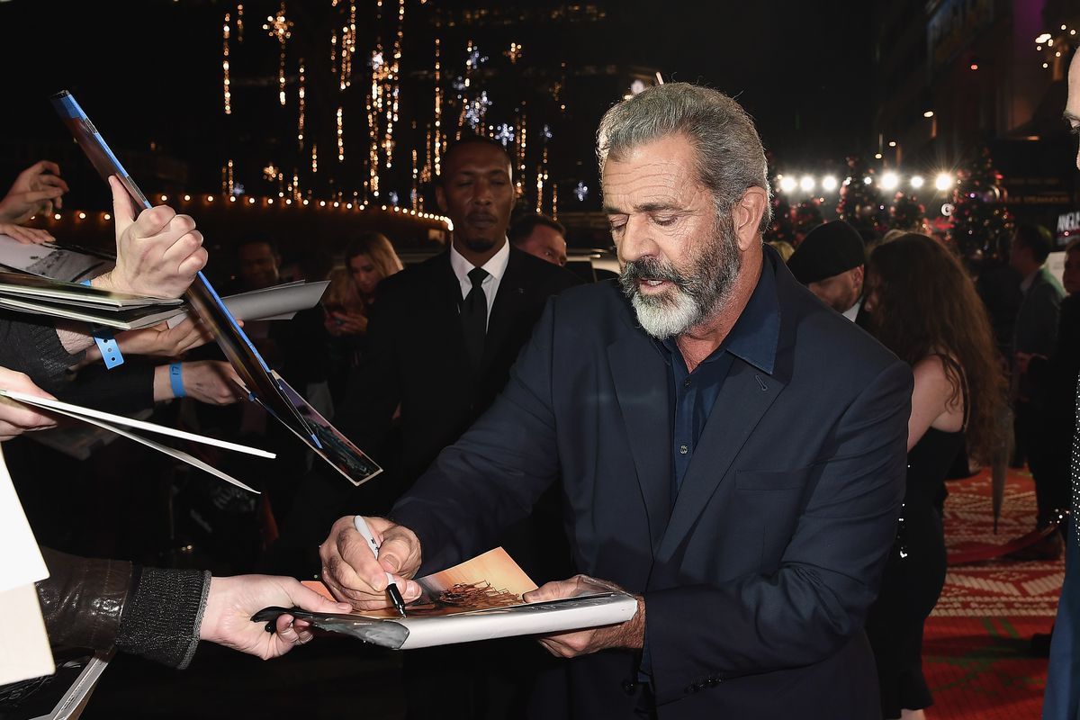 Mel Gibson in a suit signing autographs