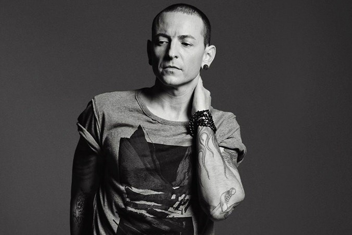 Chester Bennington resting his hand on the back of his neck with bracelets