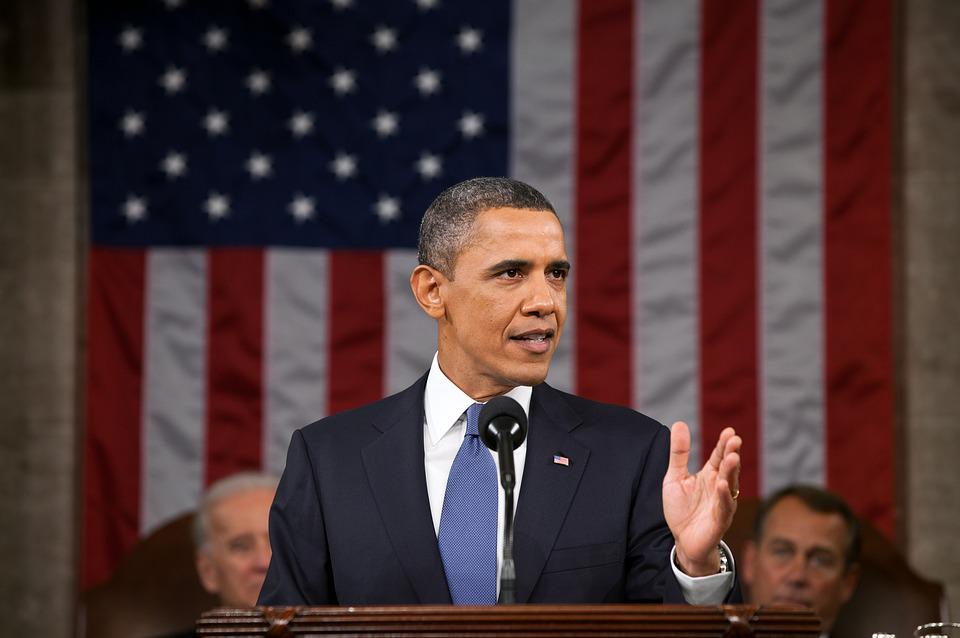 Barack Obama wearing a dark blue suit while giving a speech