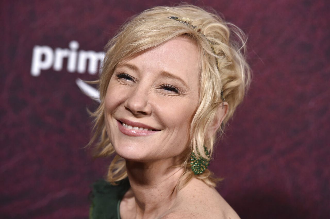Smiling Anne Heche wearing a green top and green earrings