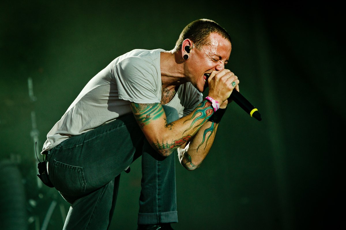 Chester Bennington singing while holding a microphone wearing a gray shirt