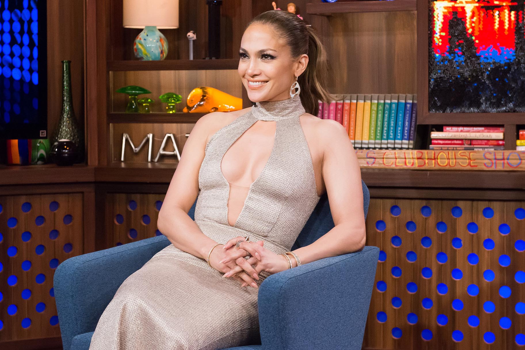 Jennifer Lopez wearing sexy silver dress while sitting on a blue couch