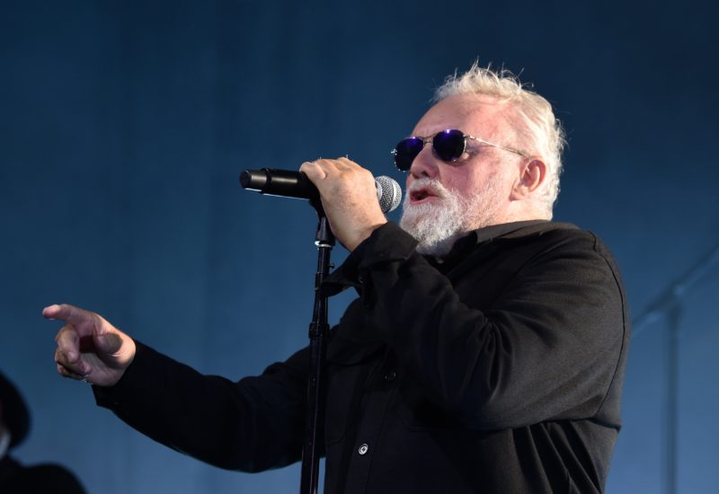 Roger Taylor Singing while holding a mic