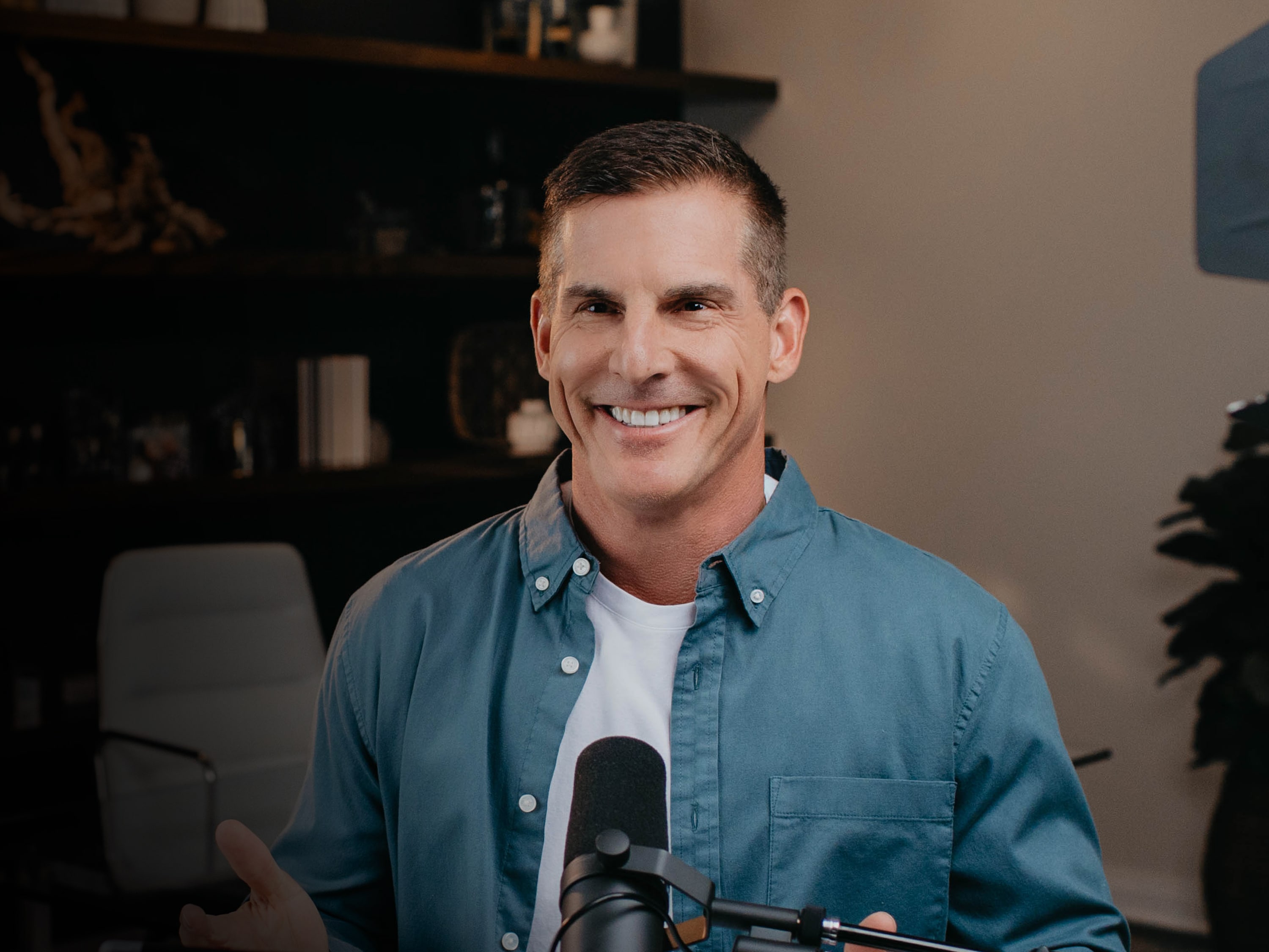 Smiling Craig Groeschel wearing a blue long sleeves and white shirt in front of a mic