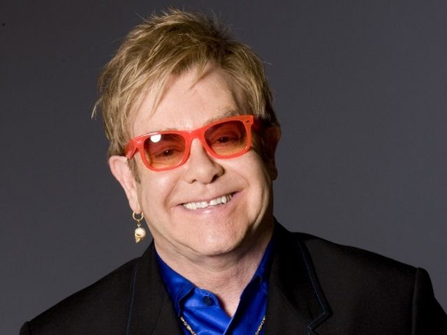 Elton Jones Smiling and wearing an orange-colored glasses