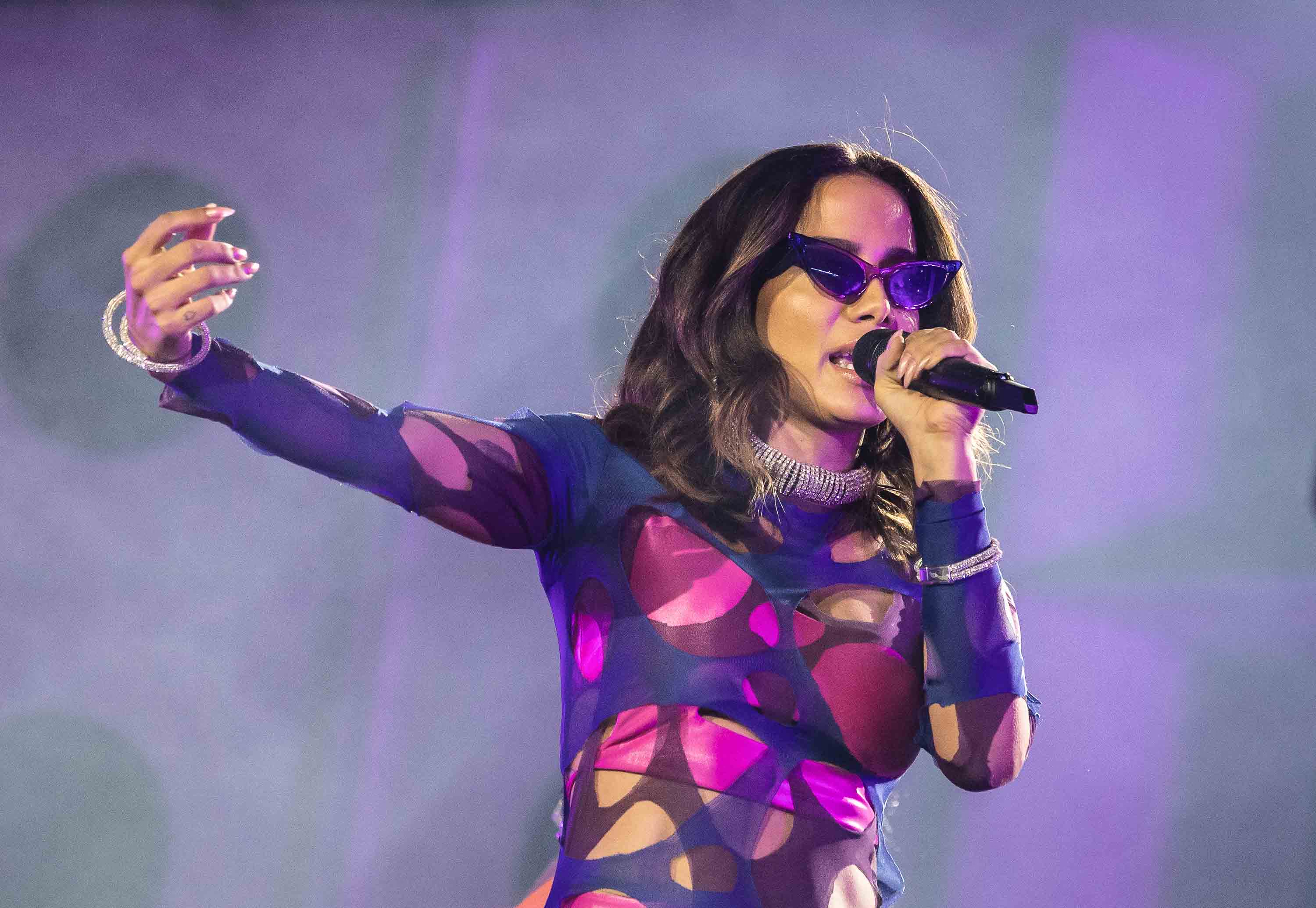 Anitta Singing on stage wearing purple and sunglasses