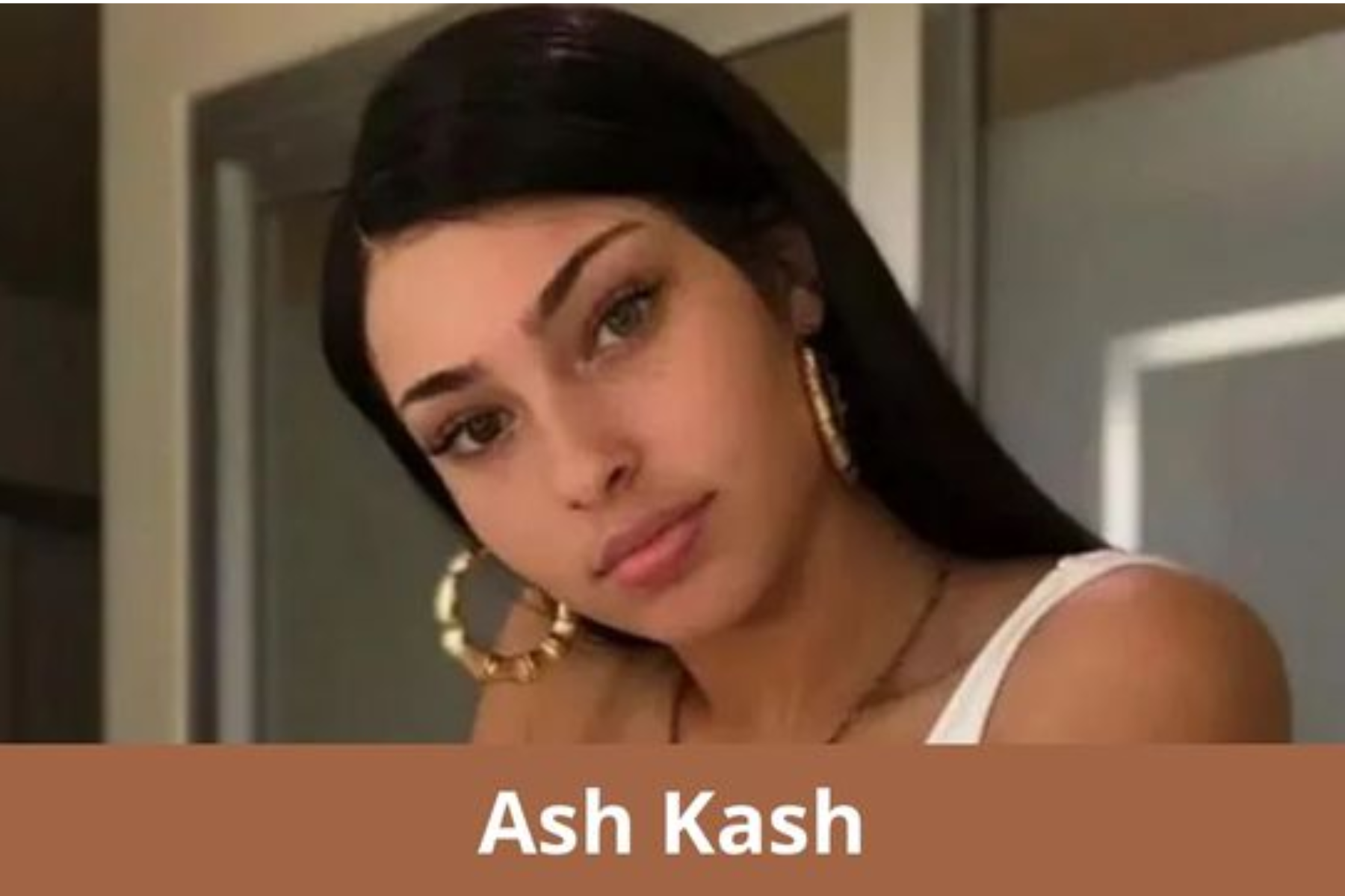 Ash Kash is wearing a massive round ring and is looking directly at the camera