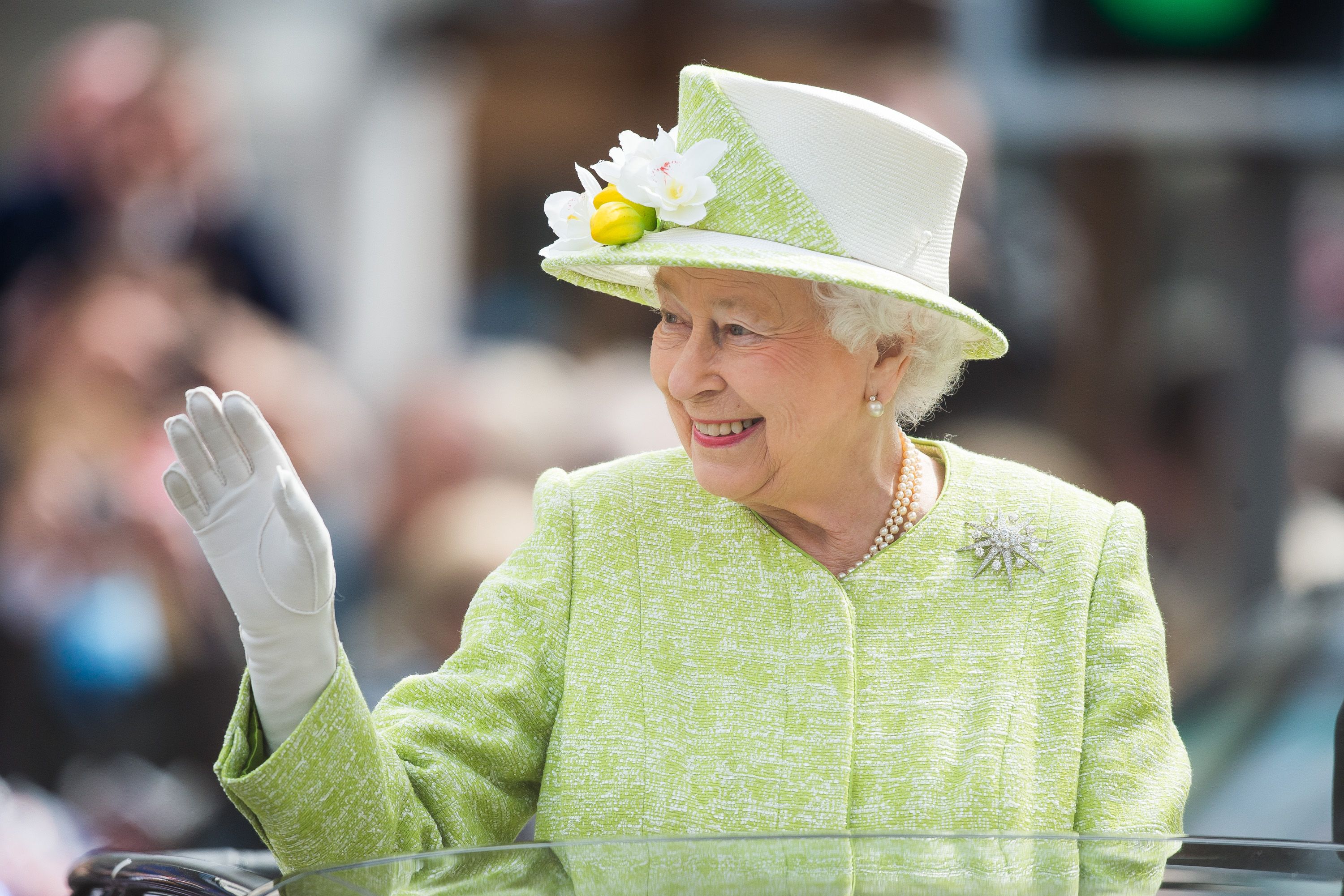 Queen Elizabeth waving her hand wearing pastel green outfit