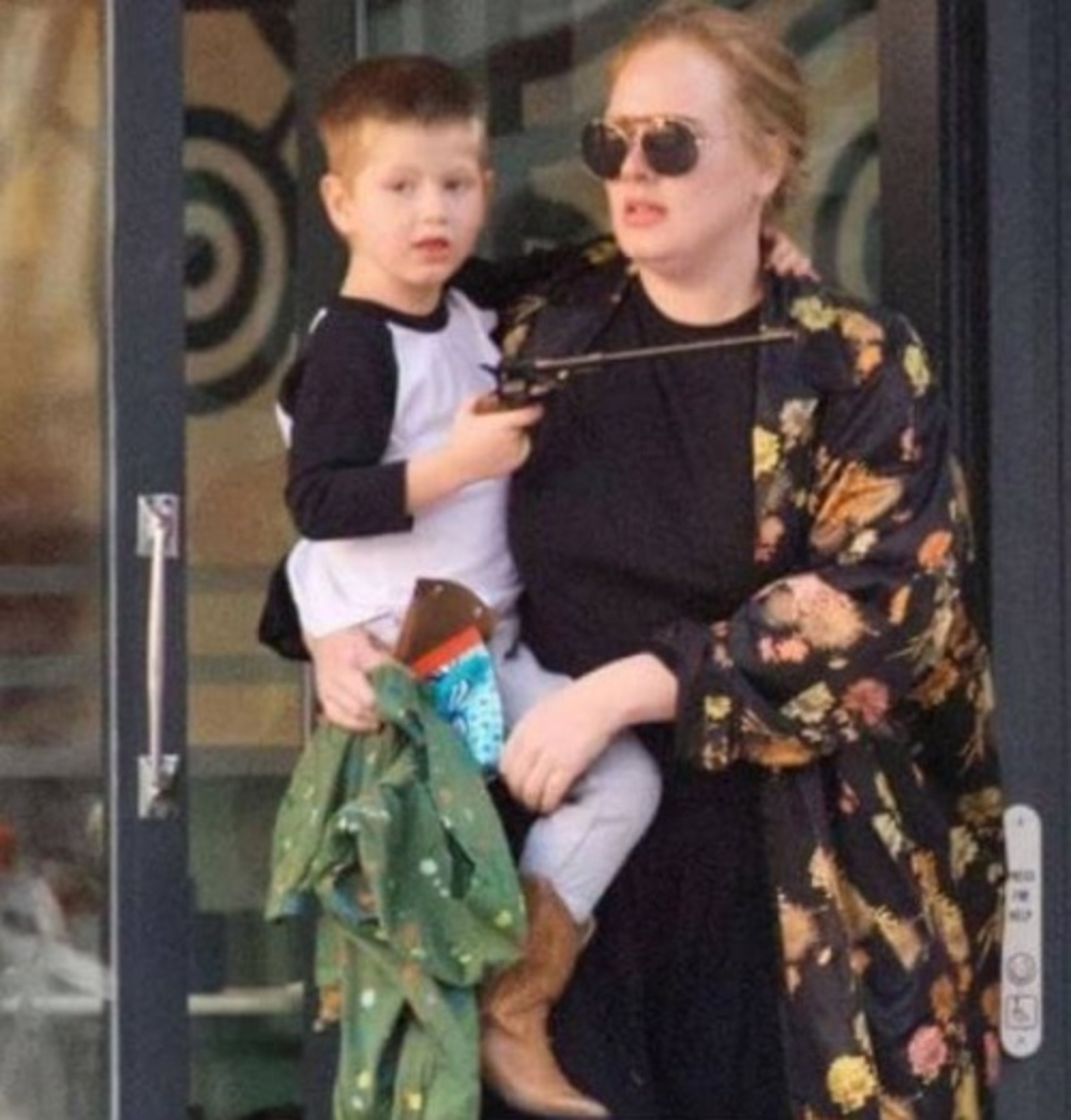 Adele carrying Angelo while coming out of a store