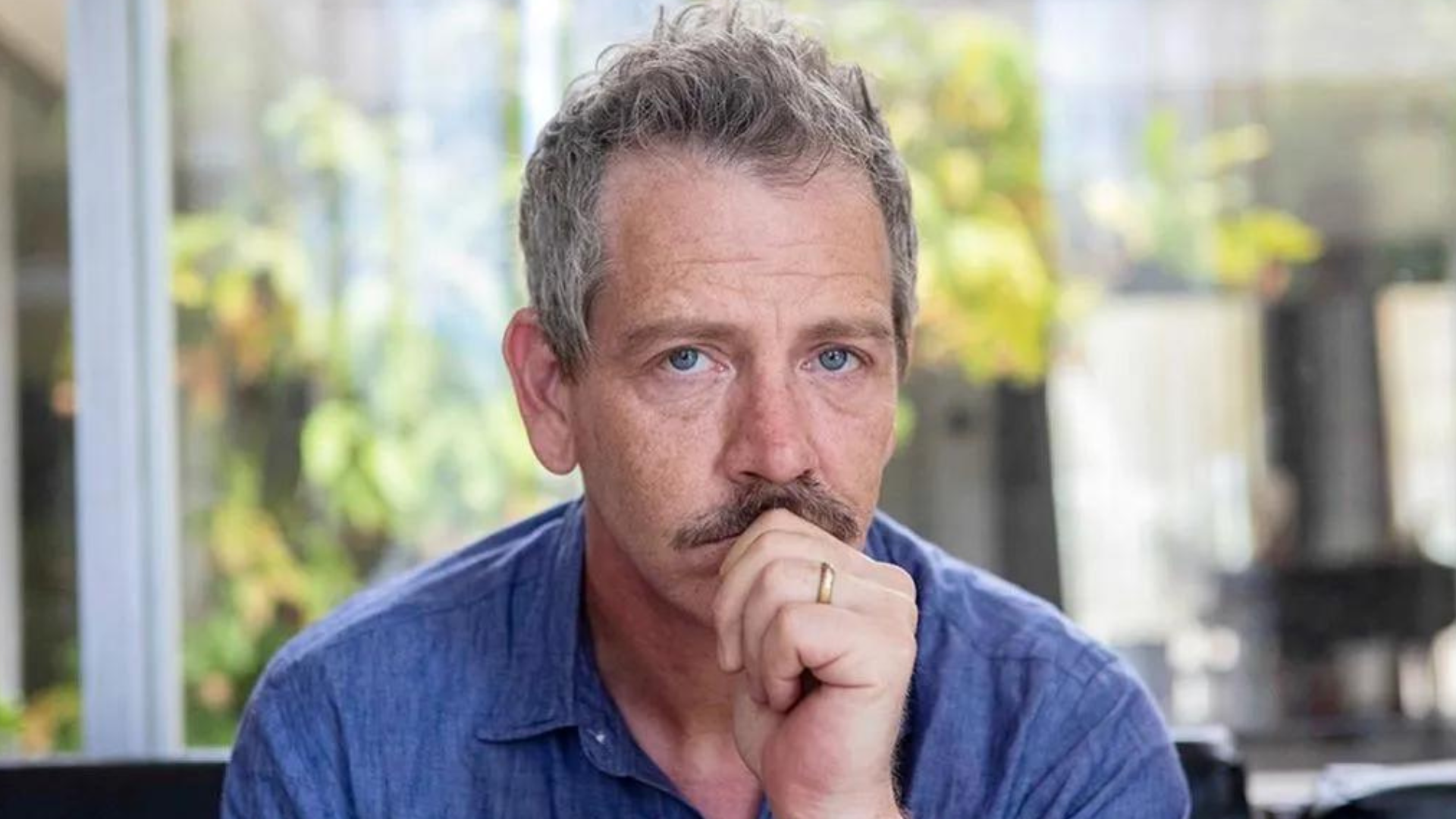 Ben Mendelsohn with a serious face and his hand on his chin