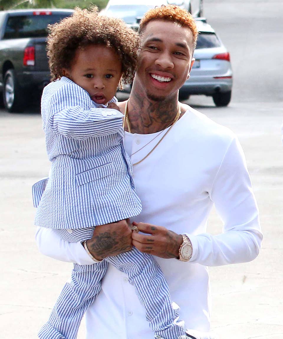 Tyga wearing white shirt while holding King Cairo Stevenson in his arms