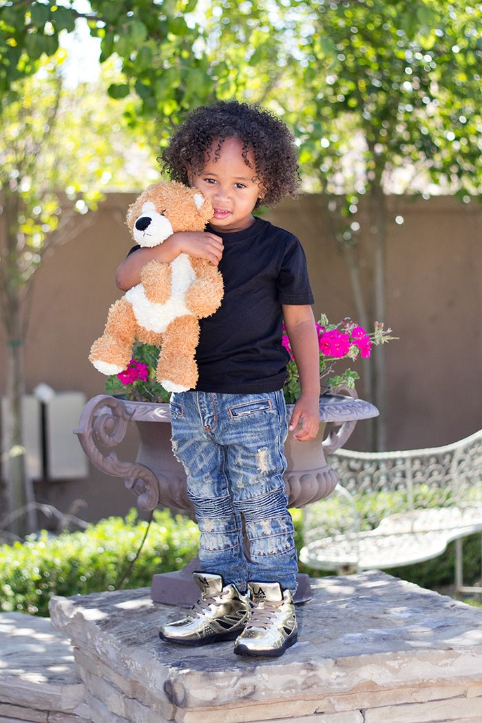 King Cairo Stevenson holding a teddy bear and wearing black shirt and pants