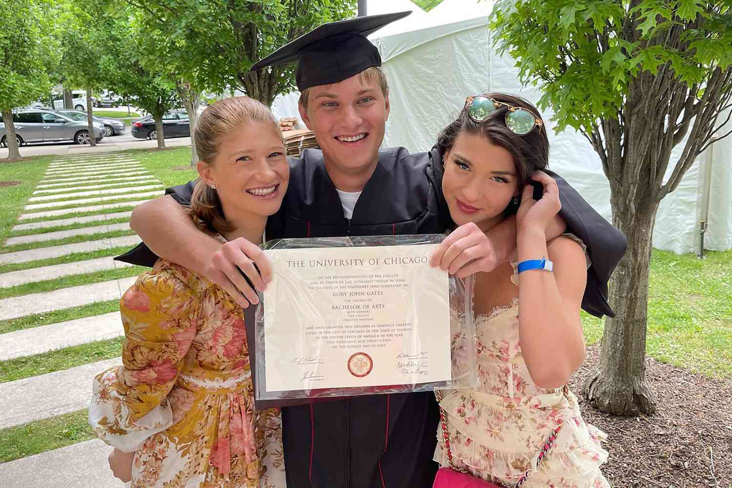 Rory John Gates wearing a graduation cap and gown with his two sisters