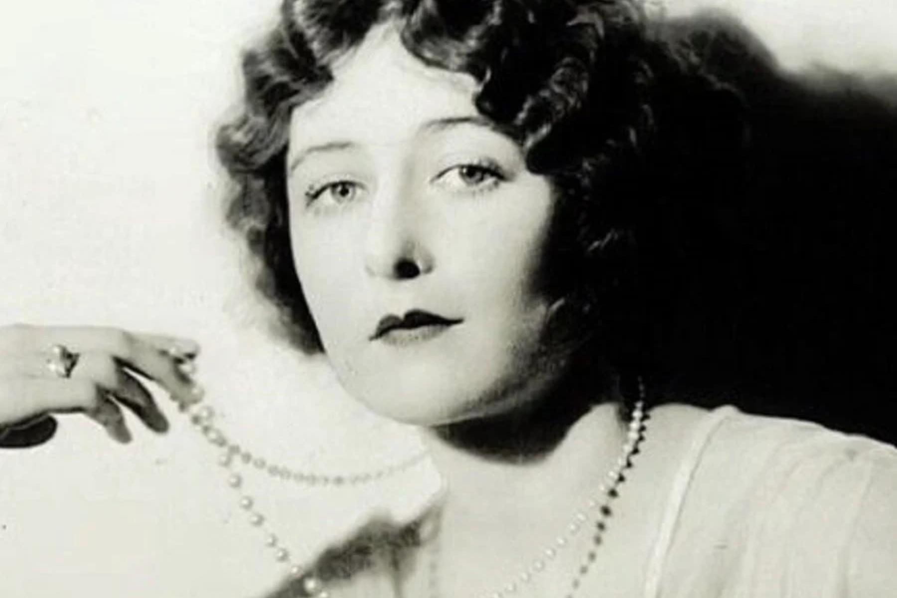 Mildred Harris poses with a pearl necklace